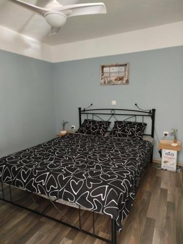 a bedroom with a black bed and a ceiling fan at B&B Hestia's Hideaway in Kalívia Thorikoú