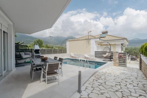 a patio with a table and chairs and a pool at Diamanti Villa, Pool & Barbecue in Skala Potamias