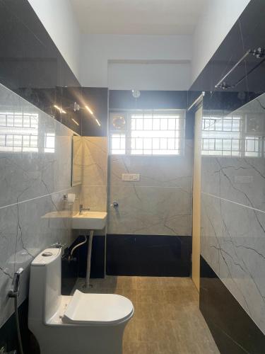 a bathroom with a toilet and a sink and a shower at Elixir Boarding & Lodging in Bangalore