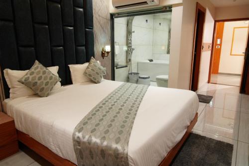 a bedroom with a large white bed and a bathroom at Hotel Bhagyalaxmi Luxury Inn in Ahmedabad