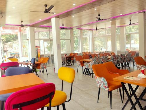 a restaurant with colorful chairs and tables and windows at cp residency in Karnaprayāg