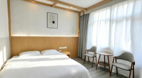 a hotel room with a bed and a table and chairs at Breeze Alley Inn-English services-3mins walk to Park-12mins to Hub-Breakfast,Coffee,Laundry&Tickets in Zhangjiajie