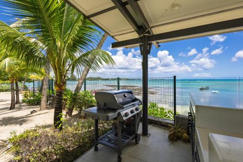 a grill on a patio with a view of the beach at Luxury Beachfront Apartment in Pereybere