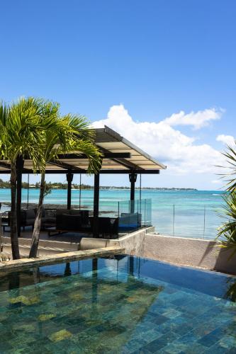 a resort with a swimming pool next to the ocean at Luxury Beachfront Apartment in Pereybere
