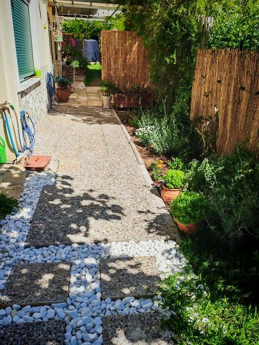 a garden with a walkway with rocks and a fence at Libelloula's apartment google it in Lygia