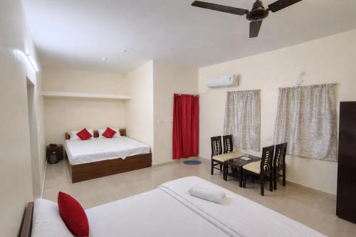a room with two beds and a table and a dining room at Ashok Nandini Guest House in Bhubaneshwar