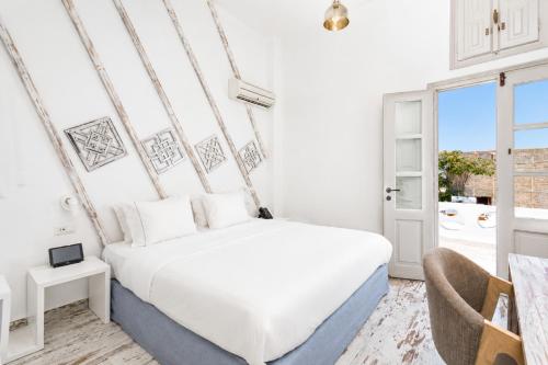 a white bedroom with a bed and a window at The Museum Project Oia in Oia