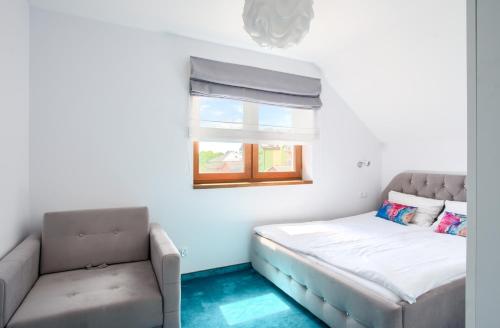 a room with a bed and a couch and a window at Domki Venus z basenem in Ustronie Morskie