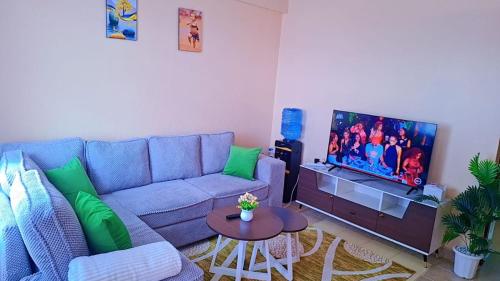 a living room with a blue couch and a tv at Tee Luxury Homes in Naivasha