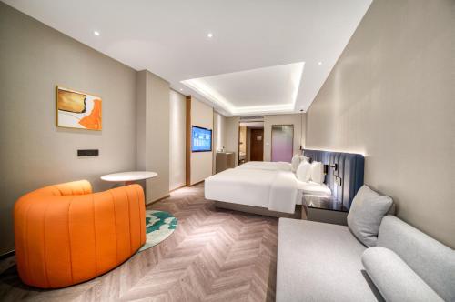 a hotel room with a bed and a couch at Ibis Styles Liyang Shanghecheng in Liyang
