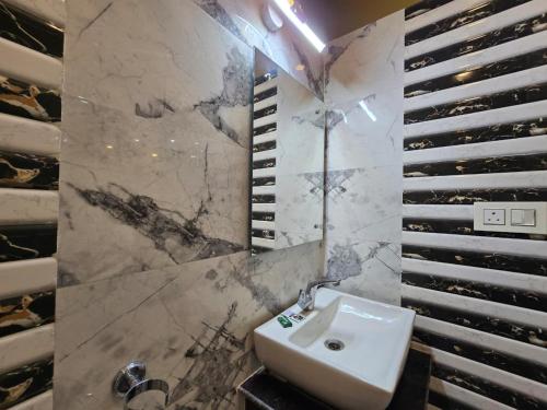a bathroom with a sink and a marble wall at RESORT SAIKAT SARANYA in Mandarmoni