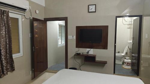 a bedroom with a bed and a television and a bathroom at Sasi Residency in Thiruchendur