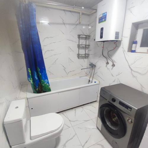 a bathroom with a toilet and a washing machine at Kamas Guesthouse in Kyzart
