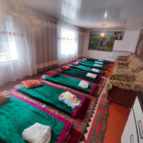 a row of beds lined up in a room at Kamas Guesthouse in Kyzart
