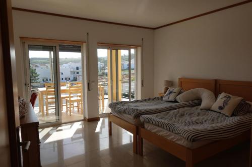 a bedroom with a bed and a balcony with sliding glass doors at Casa Lagoa Azul in Foz do Arelho