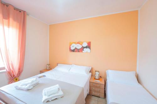 a bedroom with two white beds and a window at Casette nel Borgo in Borgagne