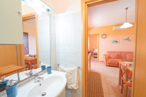 a bathroom with a sink and a living room at Casette nel Borgo in Borgagne