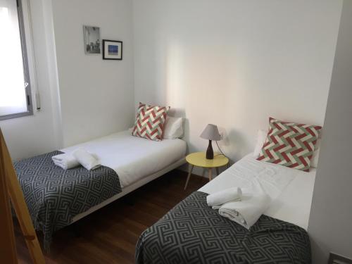 Habitación con 2 camas y mesa con lámpara. en Apartamento FIRA Barcelona en Hospitalet de Llobregat