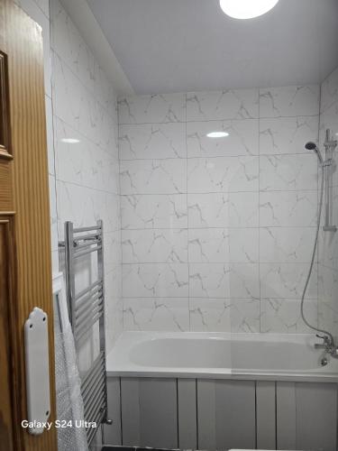 a white bathroom with a tub and a shower at J & T property in Great Coates