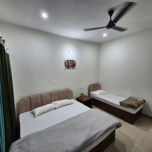 ein Schlafzimmer mit zwei Betten und einem Deckenventilator in der Unterkunft Devadidev Retreat in Gupta Kāshi