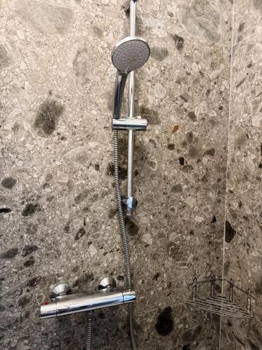 a shower with a shower head on a stone wall at Apartment Verdi BARDOLINO in Bardolino