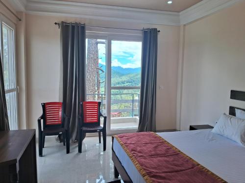 a bedroom with a bed and two chairs and a window at Shivansh Hotel in Kānda