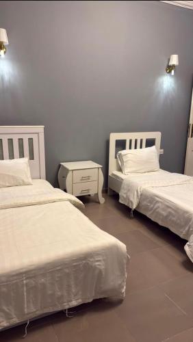 a bedroom with two beds with white sheets and a table at شالية الرايس in Rayyis