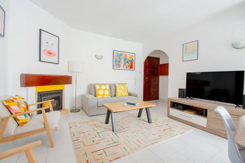 a living room with a tv and a couch and a table at Casa Sem Pressa - Beach, Pool & Central Carvoeiro in Carvoeiro