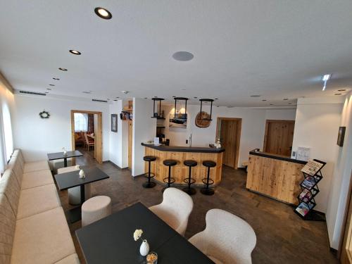 a living room with tables and chairs and a kitchen at Hotel Garni Bel-Ami in Galtür