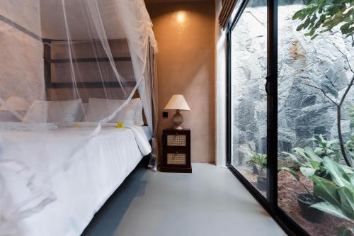 a bedroom with a bed and a large window at The Embrace Luxury Villa - Hiriketiya in Dickwella