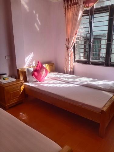 a bed with pink pillows in a room with a window at Kiên Cường Hostel in Sapa