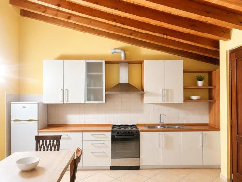 a kitchen with white cabinets and a wooden ceiling at Residenza La Torre Pizzighettone in Pizzighettone