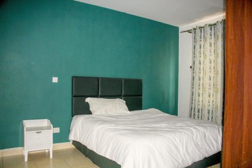 a bedroom with a bed with a green wall at Hidden Gems Homes Modern 2BR Near JKIA, Athi River in Athi River