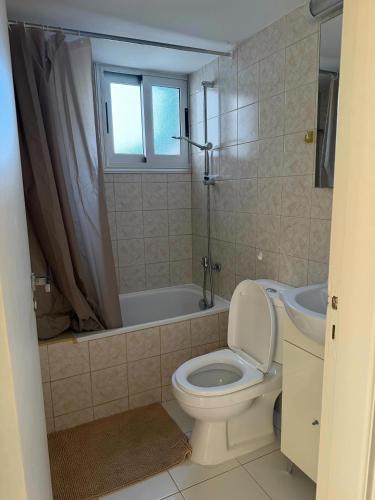 a bathroom with a toilet and a tub and a sink at Indie little house in Limassol