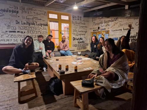 a group of people sitting around a table in a room at Laughing Leopard Hostel in Nuwara Eliya