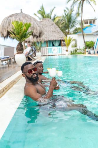 two men in a swimming pool with drinks at ZAN Jambiani Beach House in Jambiani