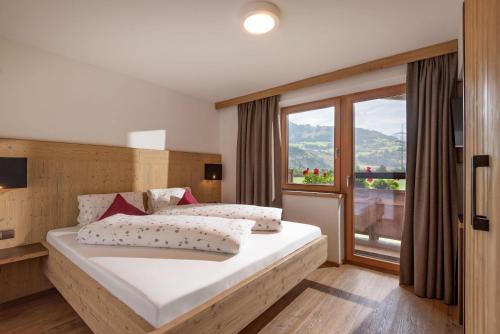 a bedroom with a large bed and a large window at Klausnerhof in Aschau
