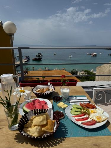 a table with plates of food and a view of the ocean at British Hotel in Himare
