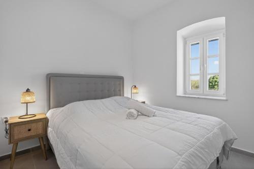 a bedroom with a large white bed with a window at Celeste Syros Retreat in Vári