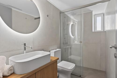 a bathroom with a sink and a toilet and a mirror at Celeste Syros Retreat in Vári
