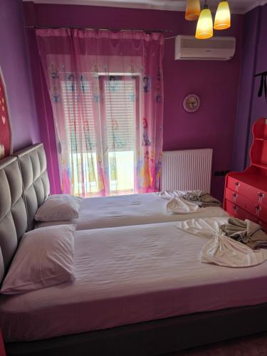 a bedroom with a bed with pink walls and a window at Alice Maisonette & Studios in Adamantas