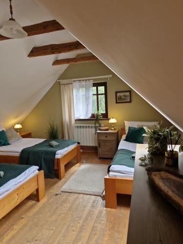 a attic bedroom with two beds and a window at Chata pod Mogielicą - klimatyczny dom na wyłączność z ogrodem i widokiem na góry in Słopnice