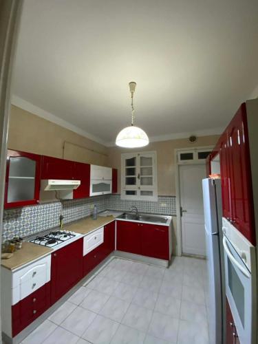 a kitchen with red cabinets and a white refrigerator at Cozy Appartement Mahdia in Mahdia