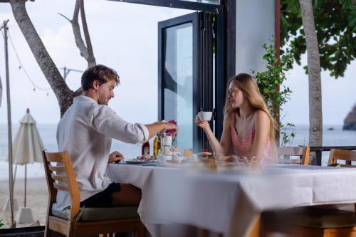 a man and woman sitting at a table with a drink at Anda Lanta Resort in Ko Lanta