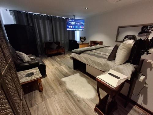 a bedroom with a bed and a couch and a chair at Mpushini Falls Resort in Eshowe