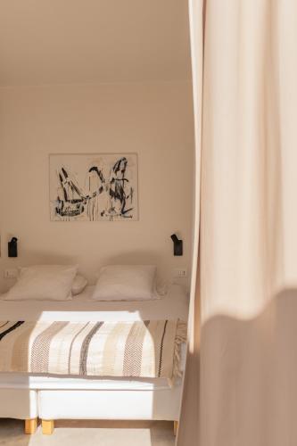 a white bedroom with a bed with a curtain at Casa Pavone in Carovigno