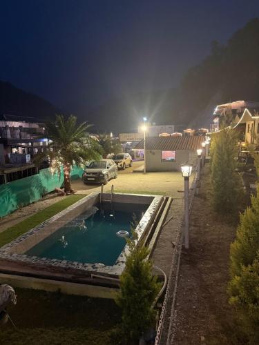 a swimming pool in a parking lot at night at Valley King Resort in Mohan Chatti