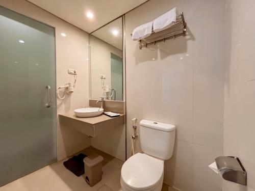 a white bathroom with a toilet and a sink at Hotel FortunaGrande Malioboro Yogyakarta in Yogyakarta