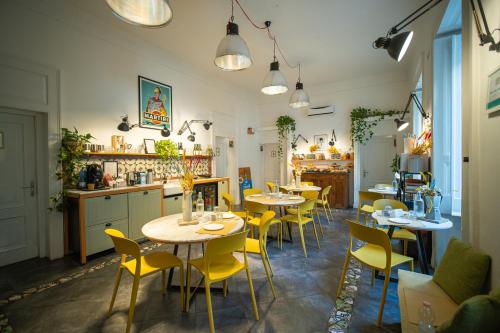 a restaurant with tables and yellow chairs in a room at Borgo Vergini Garden B&B in Naples