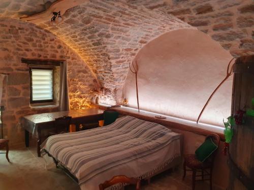a bedroom with a bed and a table in a brick wall at Studio l'envoûté in Saint-Rome-de-Tarn
